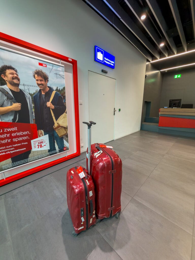 Red suitcases waiting at the SBB luggage counter inside Lucerne train station