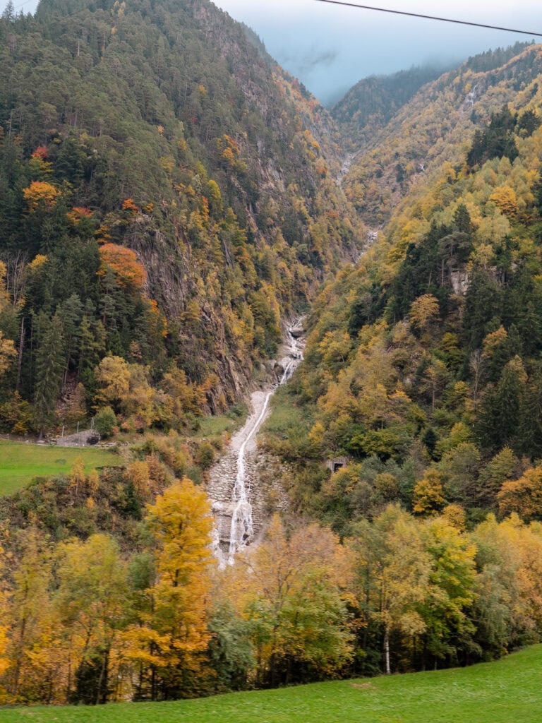 A multi-tier waterfall tumbling down the Leventina hillside, seen from the Gotthard Panorama Express train