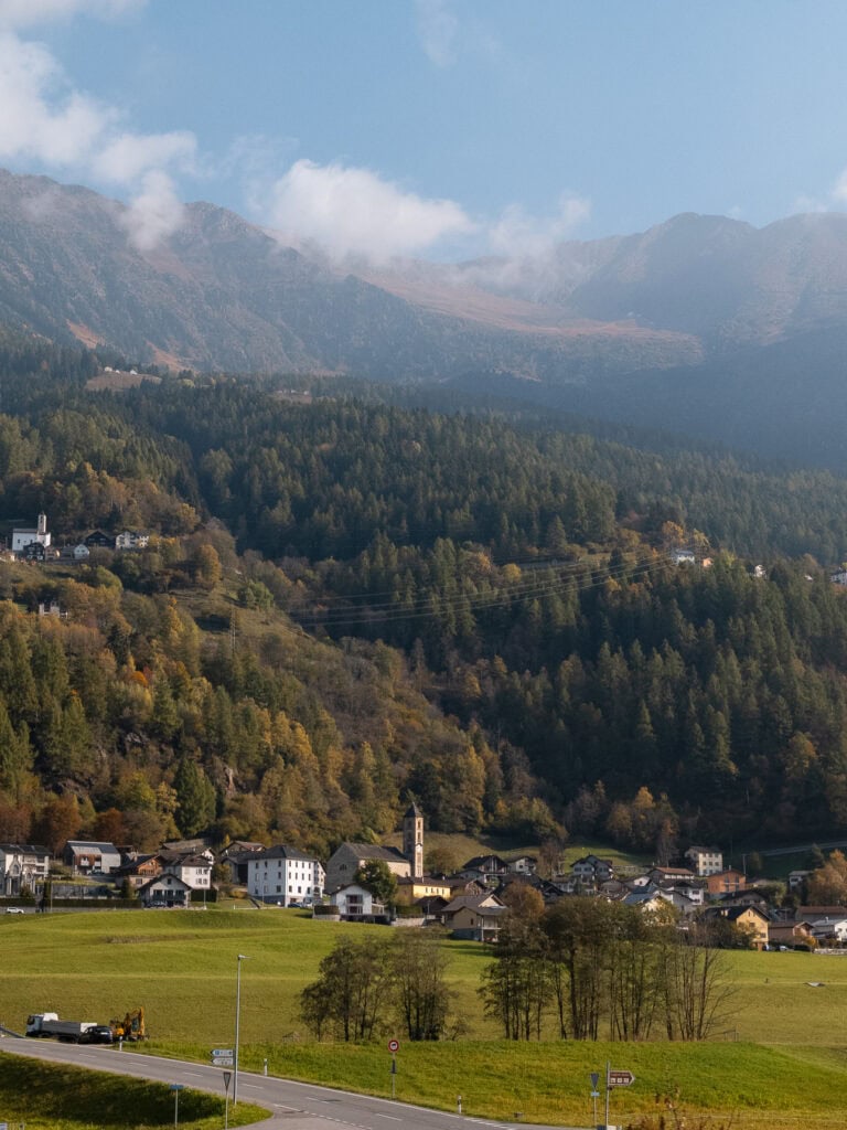 A small Swiss village with a church steeple tucked into a green valley along the Gotthard Railway