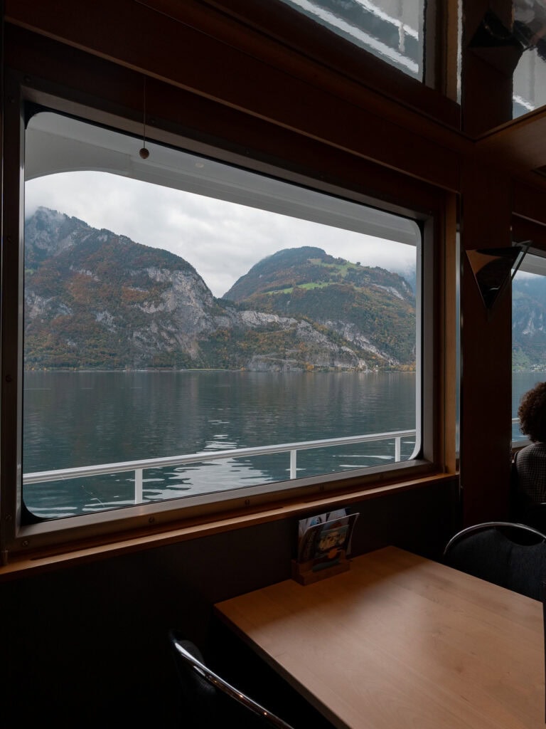 Lake Lucerne and distant mountains framed by the window of the 1st class restaurant on board a Swiss panoramic boat