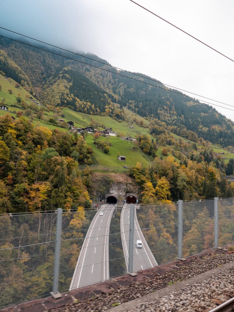 Two road tunnels emerging from a Swiss mountainside next to the Gotthard Railway track