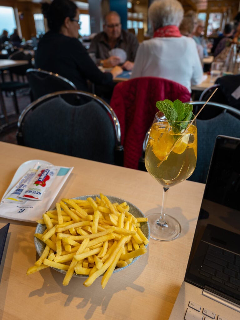 A plate of fries and a refreshing drink on a table inside the 1st class restaurant on a Lake Lucerne boat