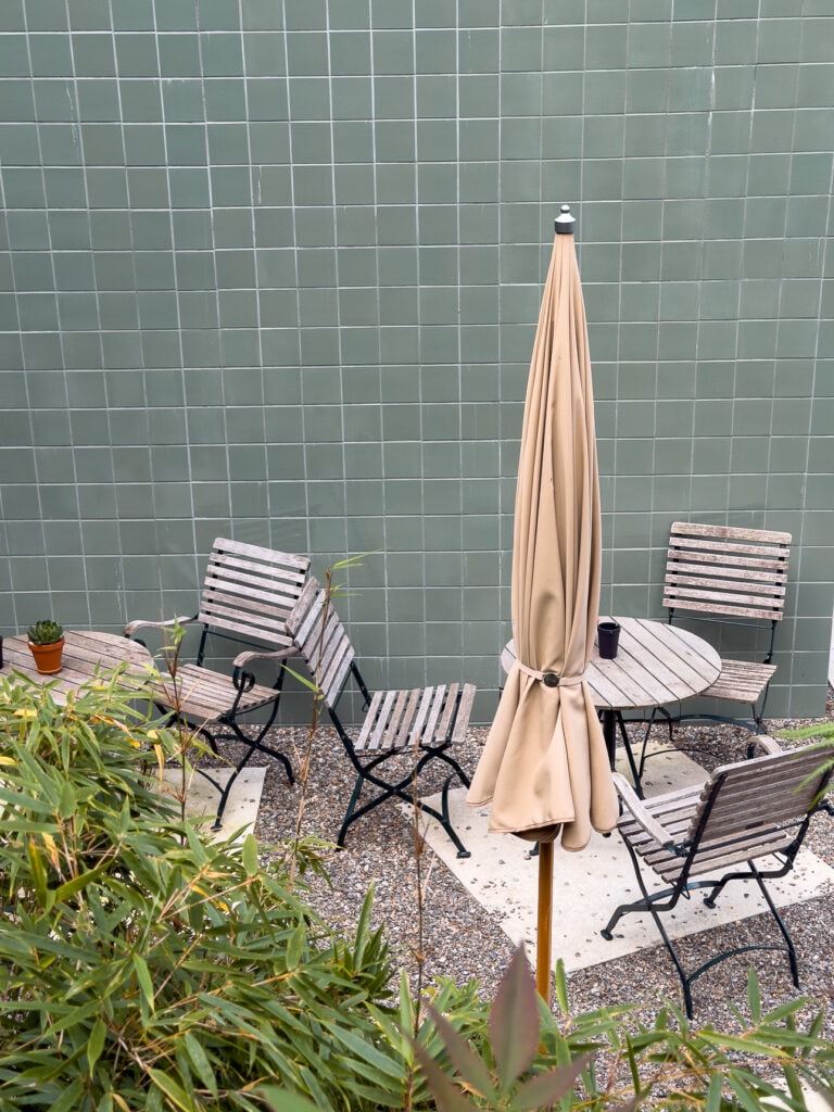 The small outdoor terrace at B5 Boutique Hotel in Lugano with tiled walls, simple seating and a sun umbrella