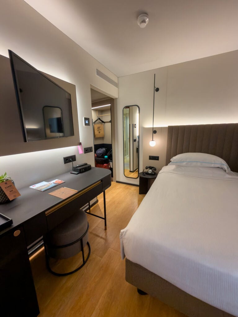 A stylish modern room at LUGANODANTE Boutique Hotel in Lugano with a large bed, desk and wall-mounted TV