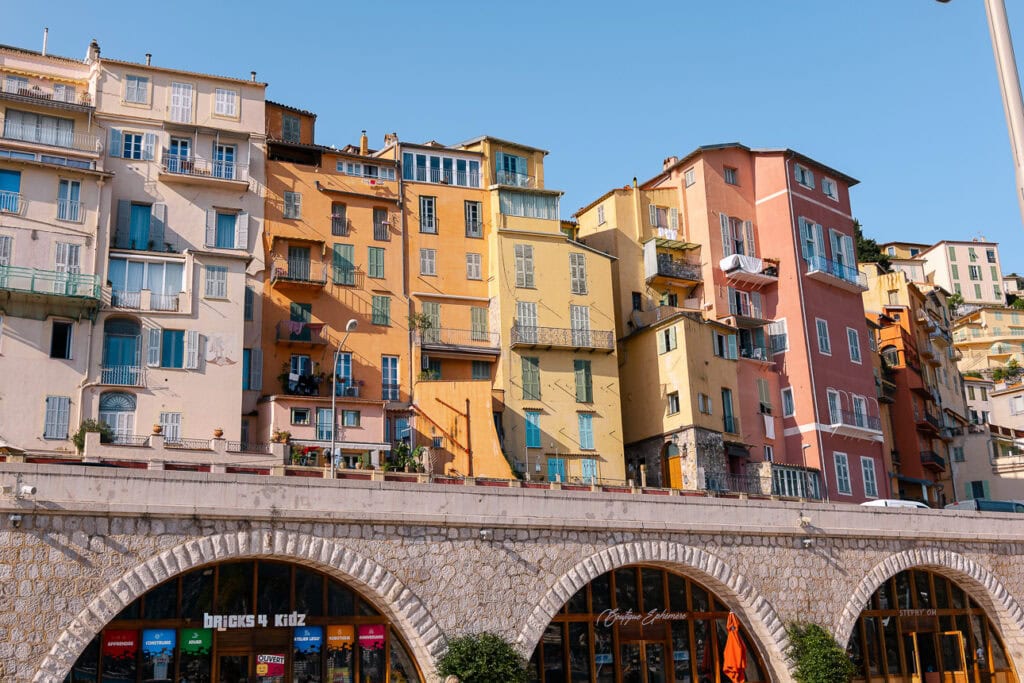Pastel apartment buildings in Menton rise above arched waterfront shops