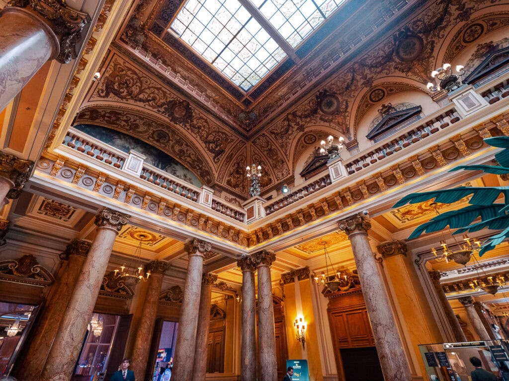 The lavish interior of Monte Carlo Casino with marble columns. Painted ceilings. Chandeliers. And a glass skylight