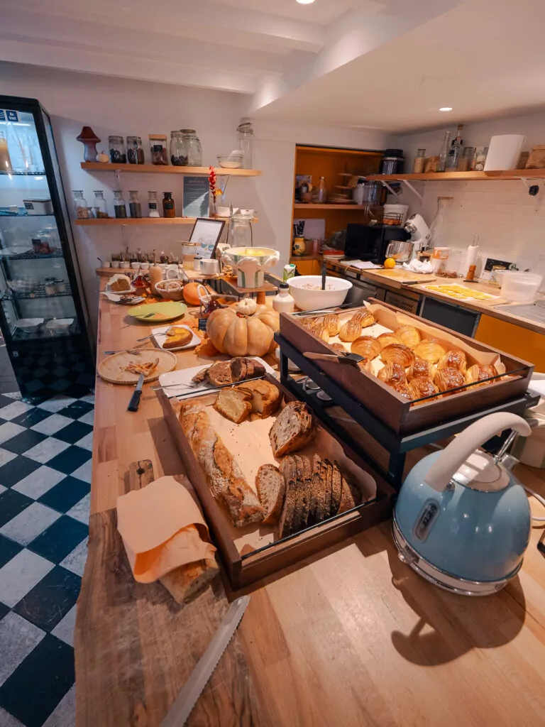 A hotel breakfast spread in Nice with fresh bread. Pastries. Fruit. Jams. And hot drinks laid out on a wooden counter at Maison Durante.