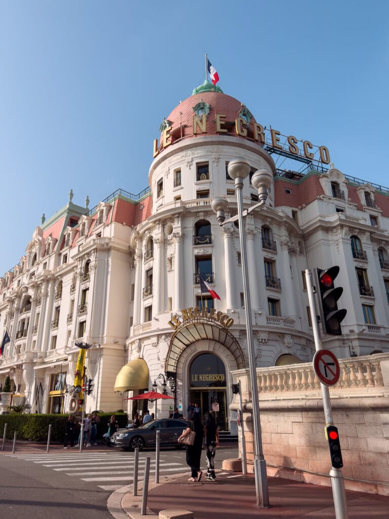 The ornate pink and white facade of Hotel Le Negresco in Nice. The sign reads "Le Negresco"
