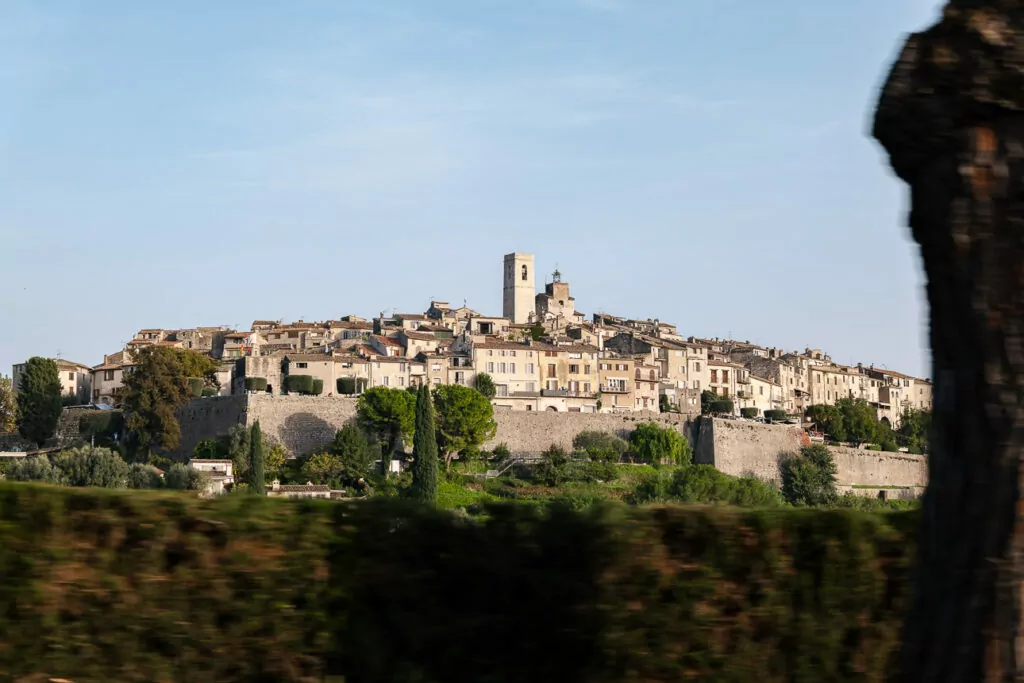 Saint Paul de Vence sits on a hilltop behind stone walls and greenery. The village skyline shows why it is worth the bus connection from the coast