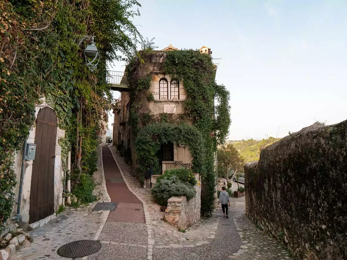 A narrow lane in Saint Paul de Vence curves past an ivy covered stone building. The medieval village is an inland highlight for a French Riviera without a car itinerary