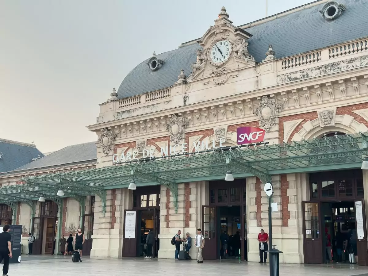 The front of Gare de Nice Ville with travellers standing outside. This is the main train station for starting a French Riviera without a car itinerary