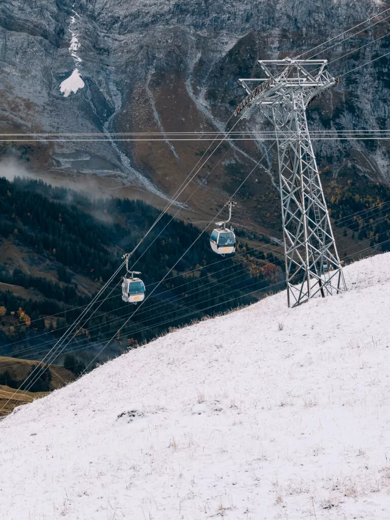 Grindelwald First gondolas travelling above snowy slopes and alpine cliffs