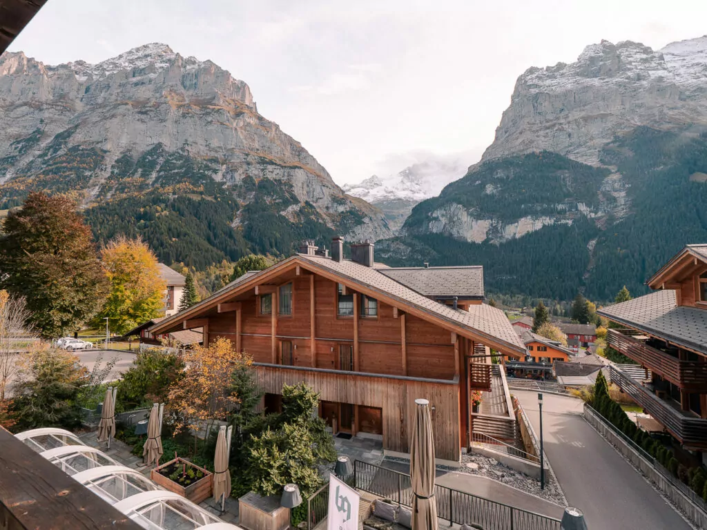 Wooden chalets in Grindelwald with mountain peaks behind them
