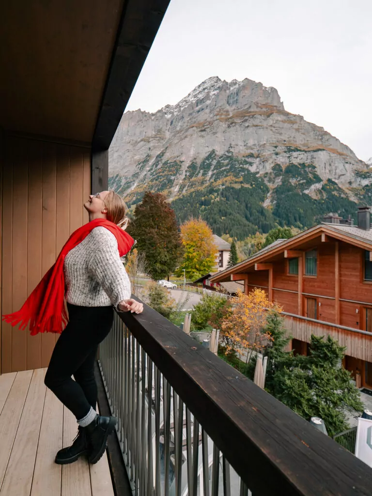 Traveller on a balcony in Grindelwald looking towards the mountains and wooden chalets