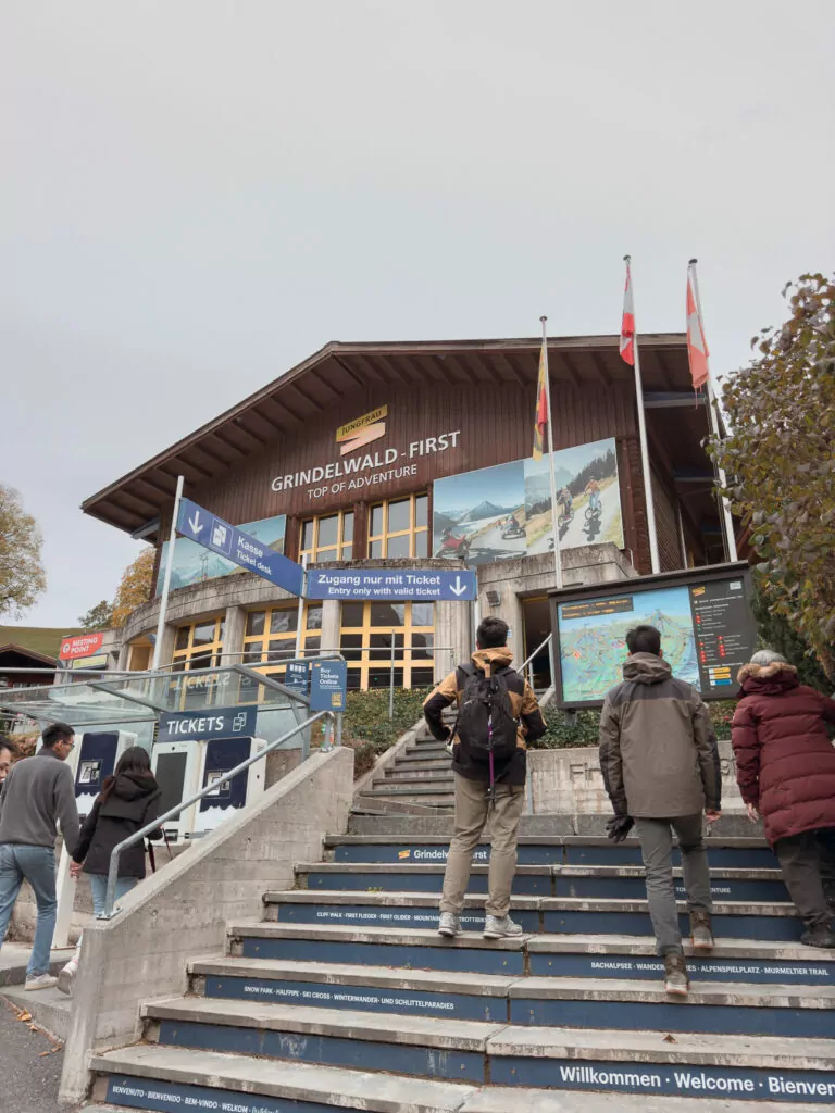 Entrance to the Grindelwald First cable car station with travellers walking up the steps