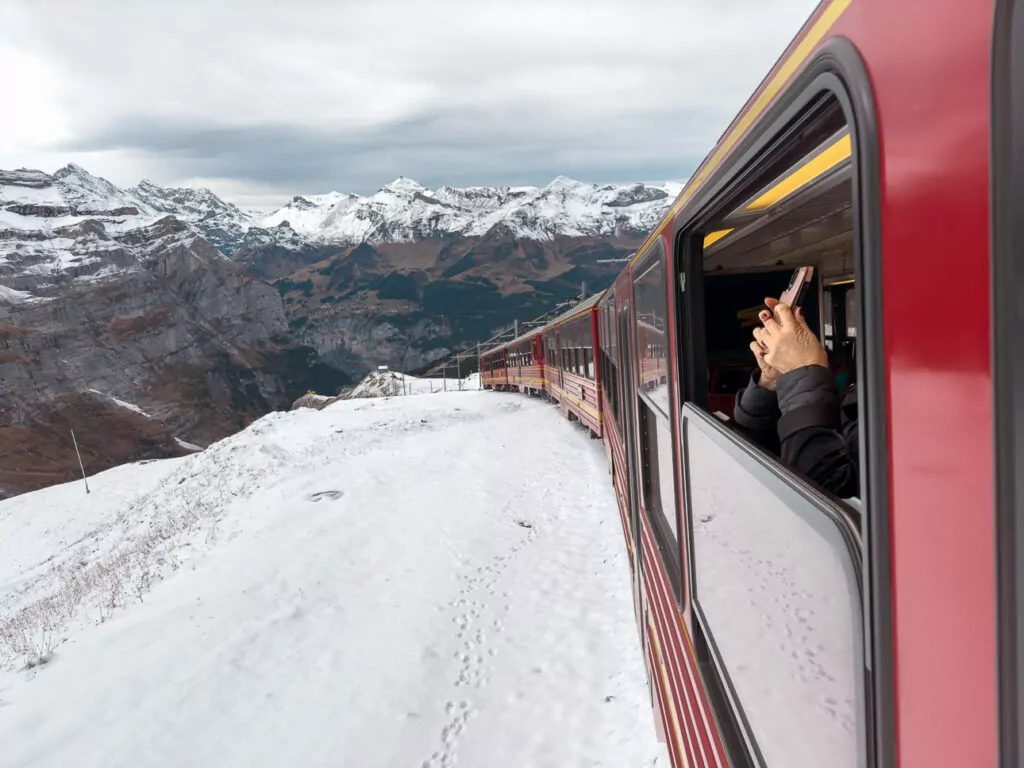 Red Jungfrau Railway train travelling through snowy mountain scenery