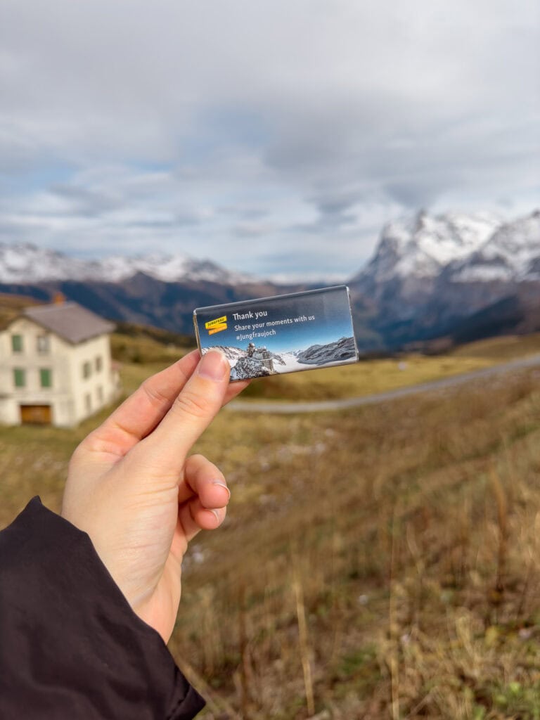 Jungfraujoch-branded chocolate bar held in front of blurred mountain scenery