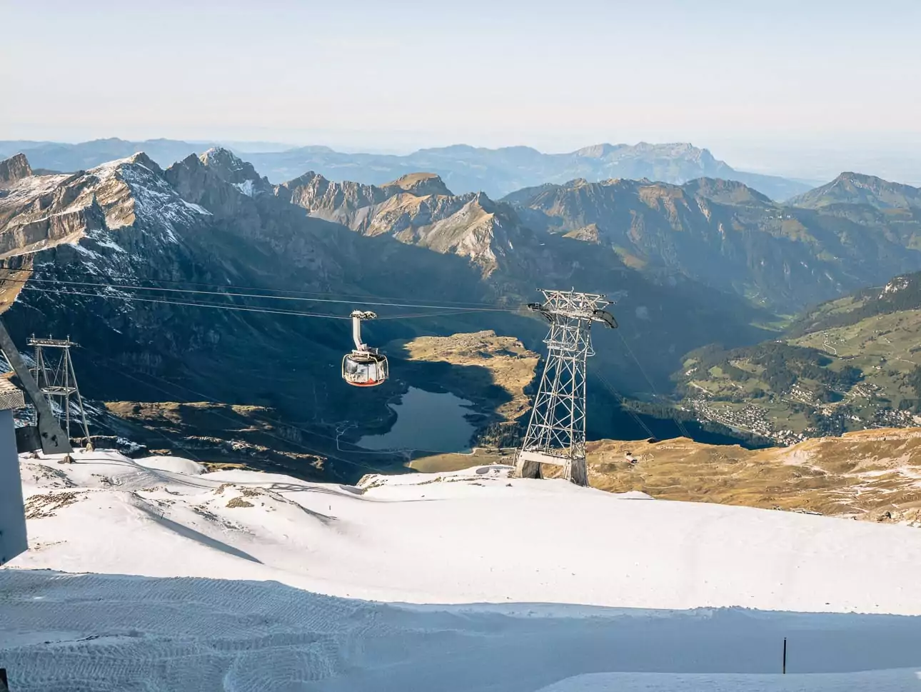 Titlis Rotair cable car above snowy slopes, Lake Trübsee and the Engelberg mountains