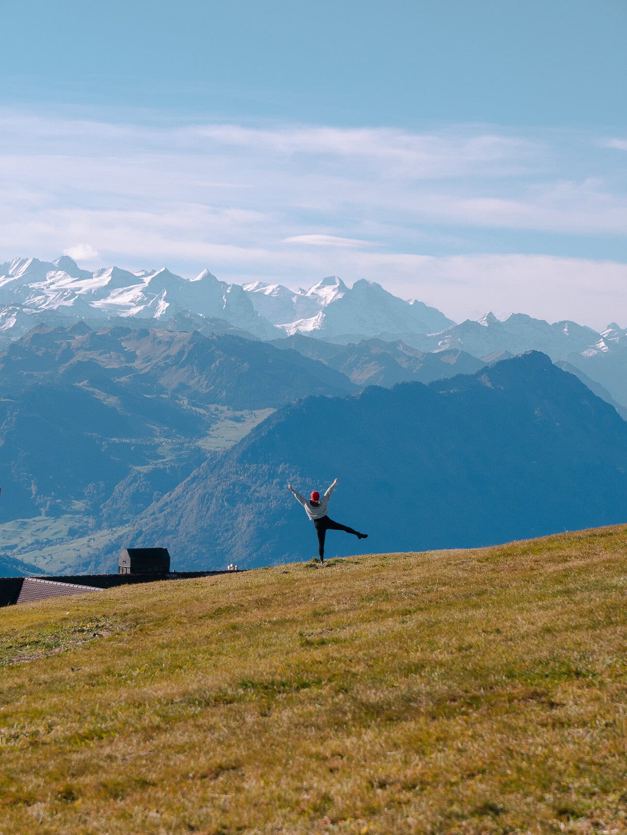 Traveller posing on a grassy hillside at the top of Mount Rigi with Swiss Alps mountain views in the background