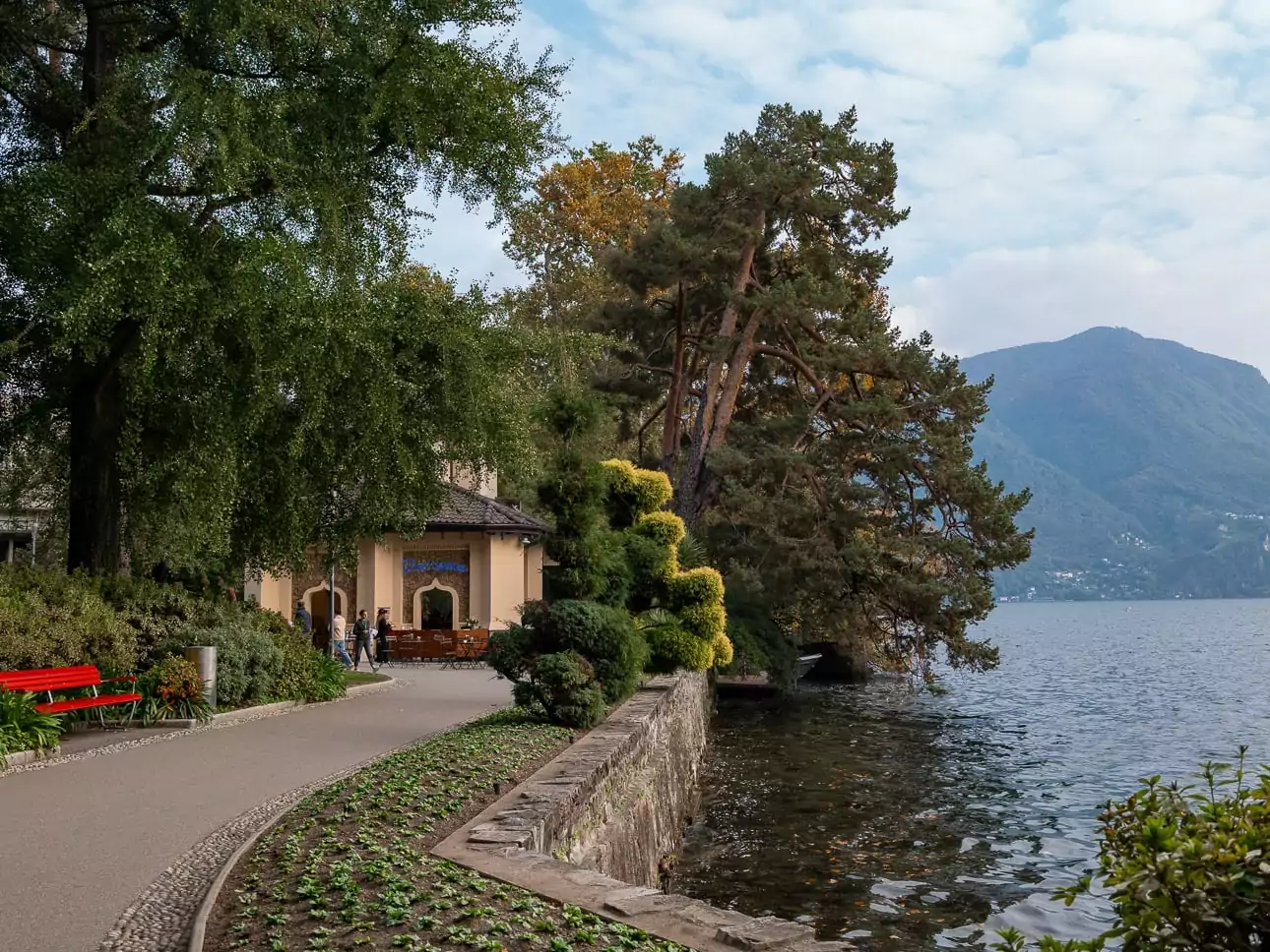 Lugano lakeside promenade with trees, mountains and Lake Lugano