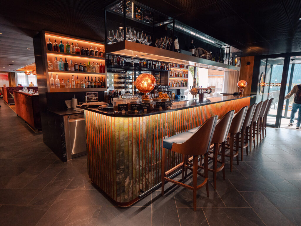 Bergwelt Grindelwald bar with a long wooden counter, backlit bottles, and alpine-lodge atmosphere