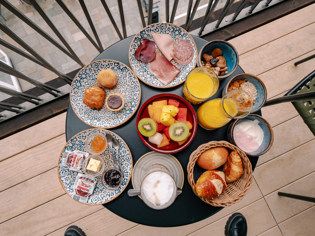 Breakfast spread at Bergwelt Grindelwald with pastries, fresh fruit, coffee, and juice laid out on a table