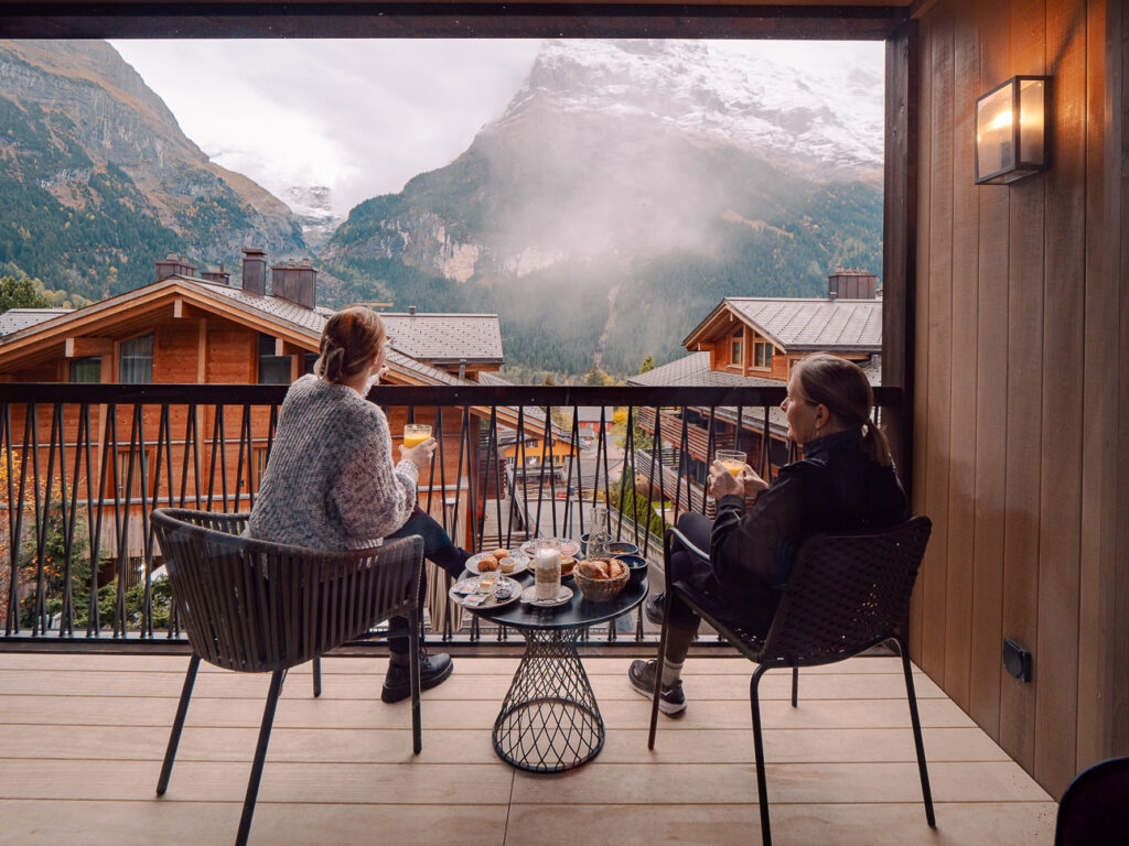 Bergwelt Grindelwald balcony with two people looking out at snow-covered mountains