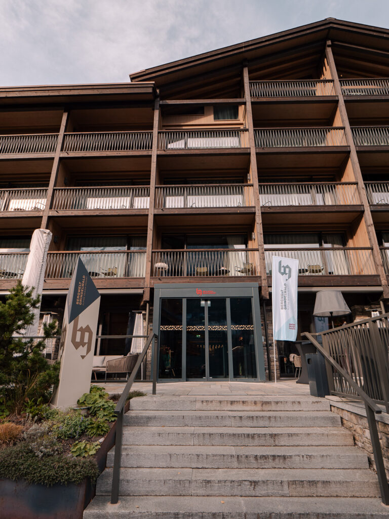 Exterior of Bergwelt Grindelwald showing its modern dark-wood alpine architecture and tiered balconies
