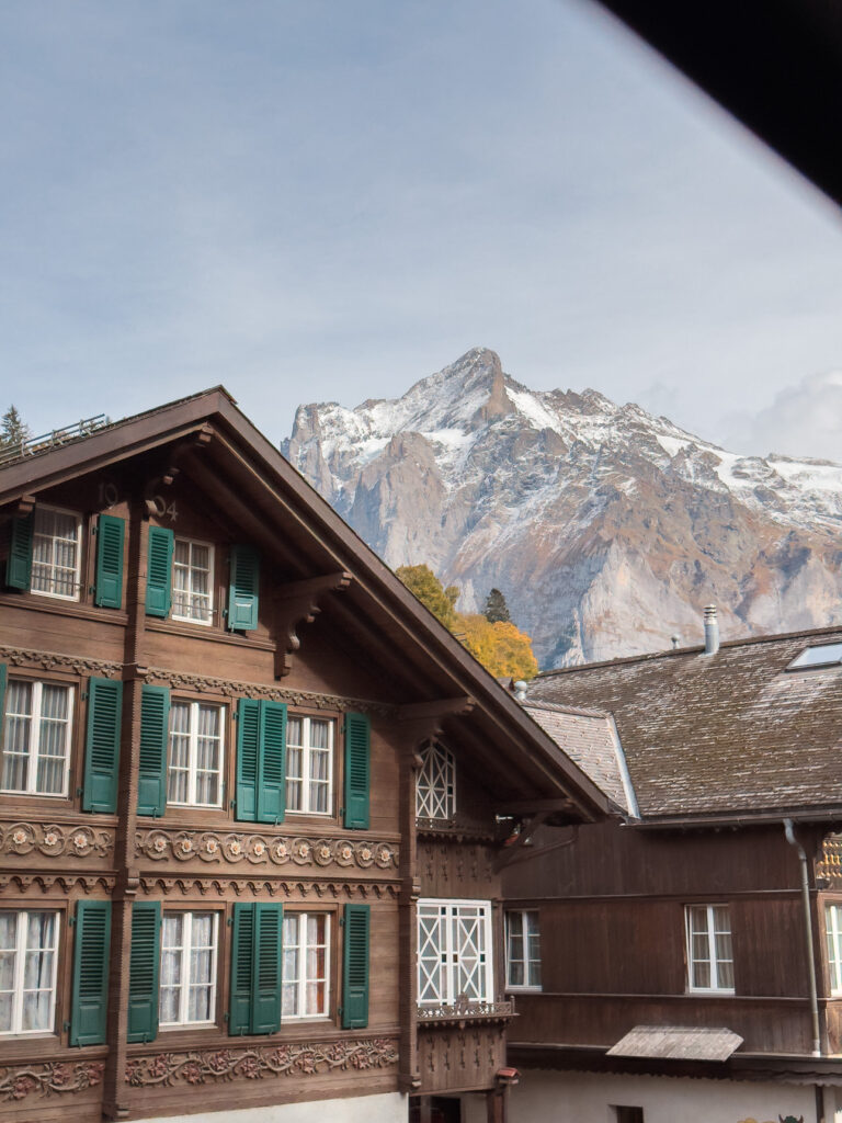 Traditional wooden chalets in Grindelwald village with the Eiger mountain rising behind them, seen from the train