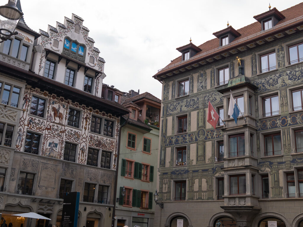 Painted facades of Lucerne Old Town houses with Swiss and cantonal flags on a corner oriel
