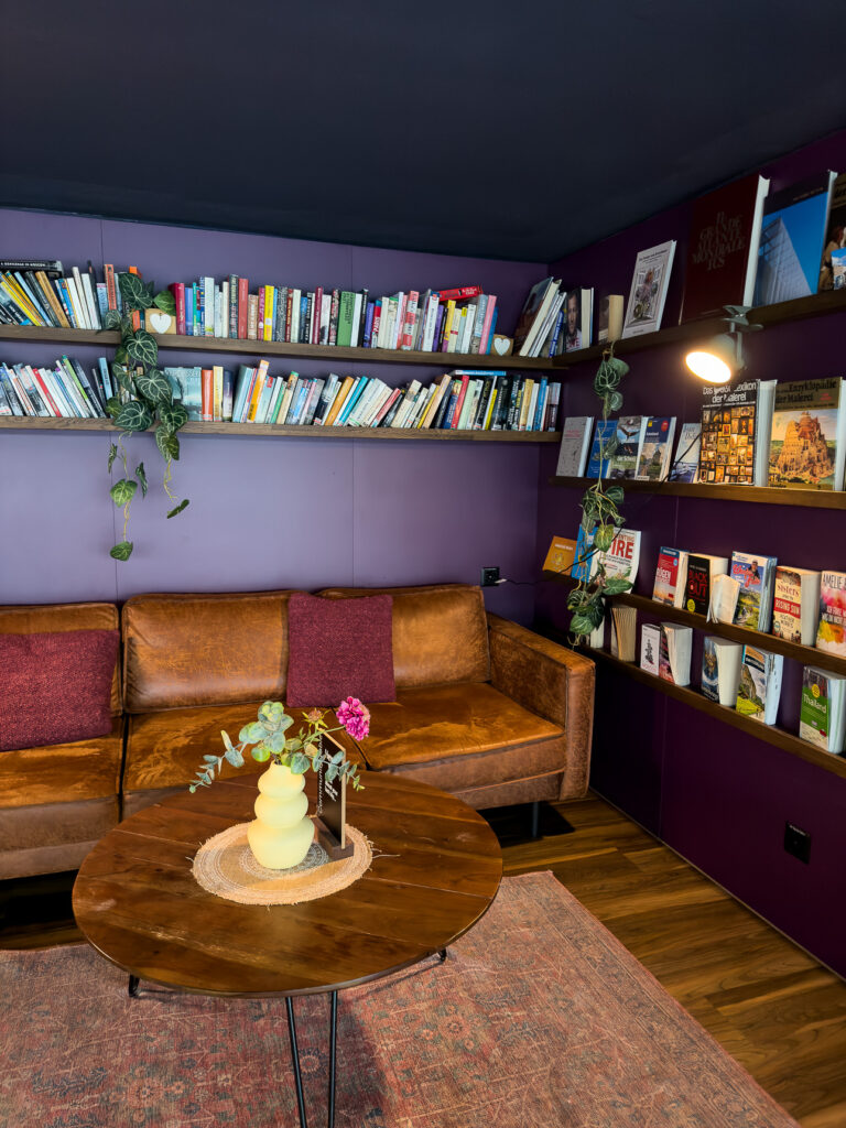 Reading corner with a leather sofa and shelves of books and magazines against purple walls