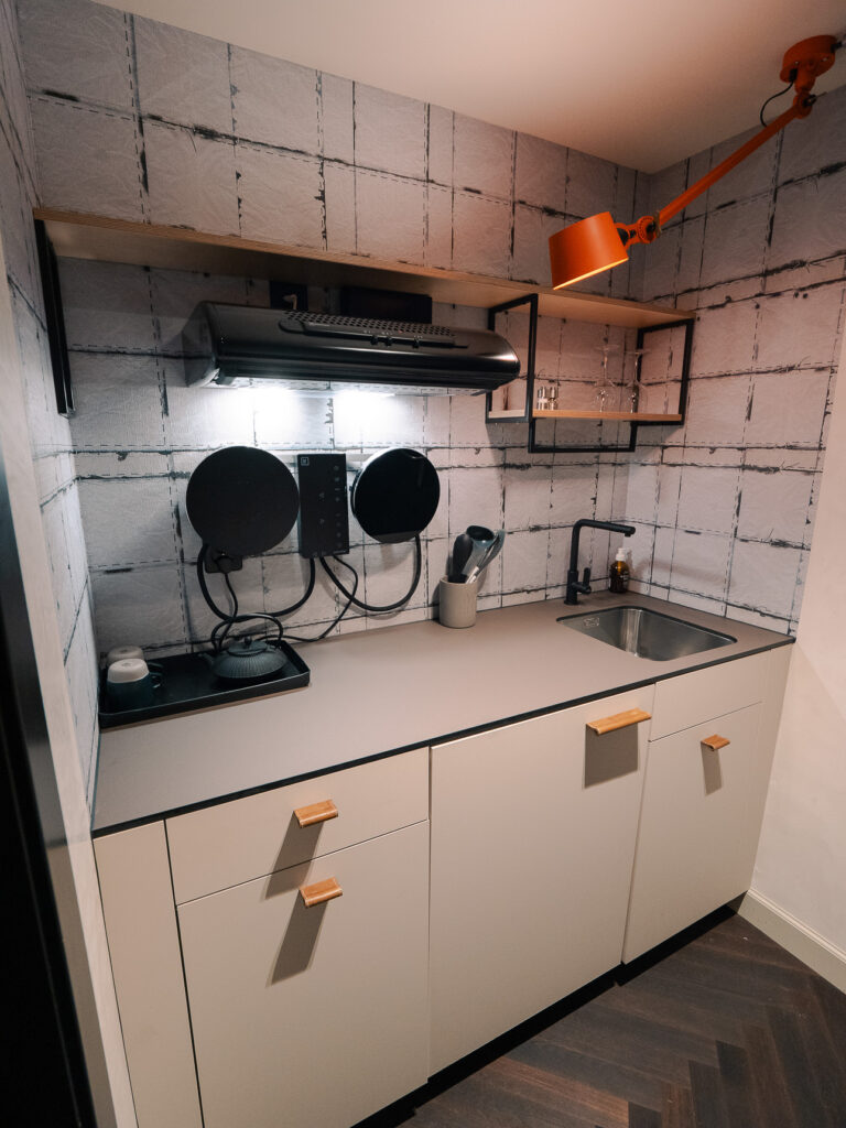 Kitchenette with two induction hob plates, an extractor hood, kettle and sink at The Lubo