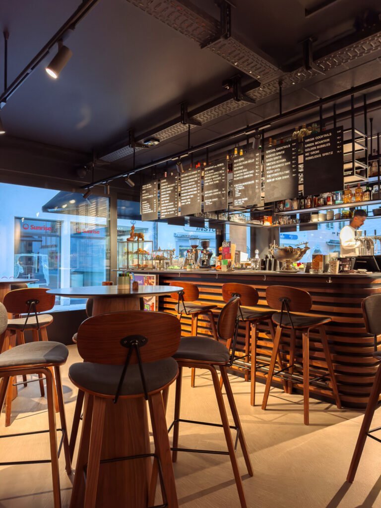 Cafe bar with chalkboard menus above the counter, wooden stools and high tables